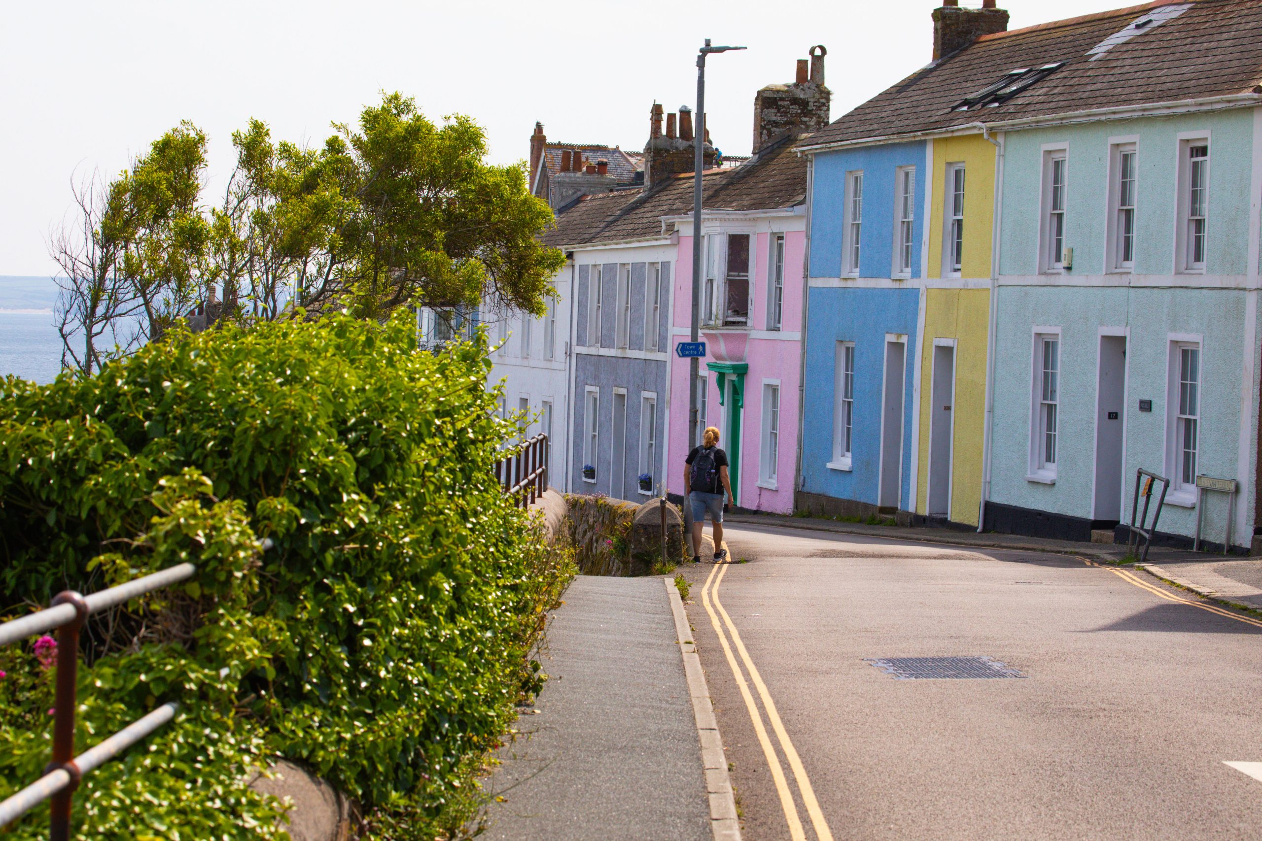 Charming pastel houses in St Ives, England with a person walking along the street.